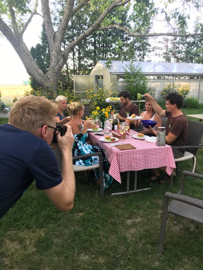 Wolfgang Lehner fotografiert kniend eine Tischrunde im Garten des Biohofs ADAMAH